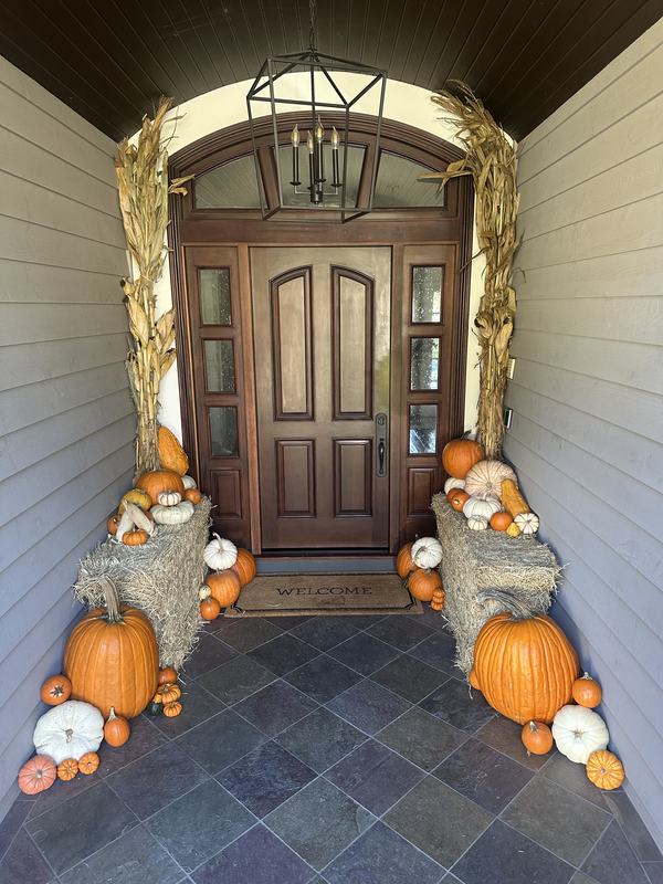 Wood door entry with hay bales, corn stalks and layered pumpkins