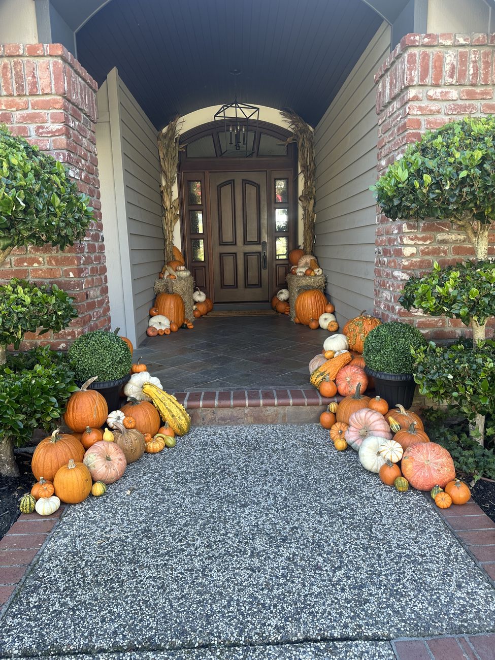 Arched front entry lined with pumpkins, gourds and corn stalks