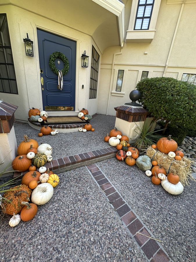 Navy front door framed by pumpkins and hay bales