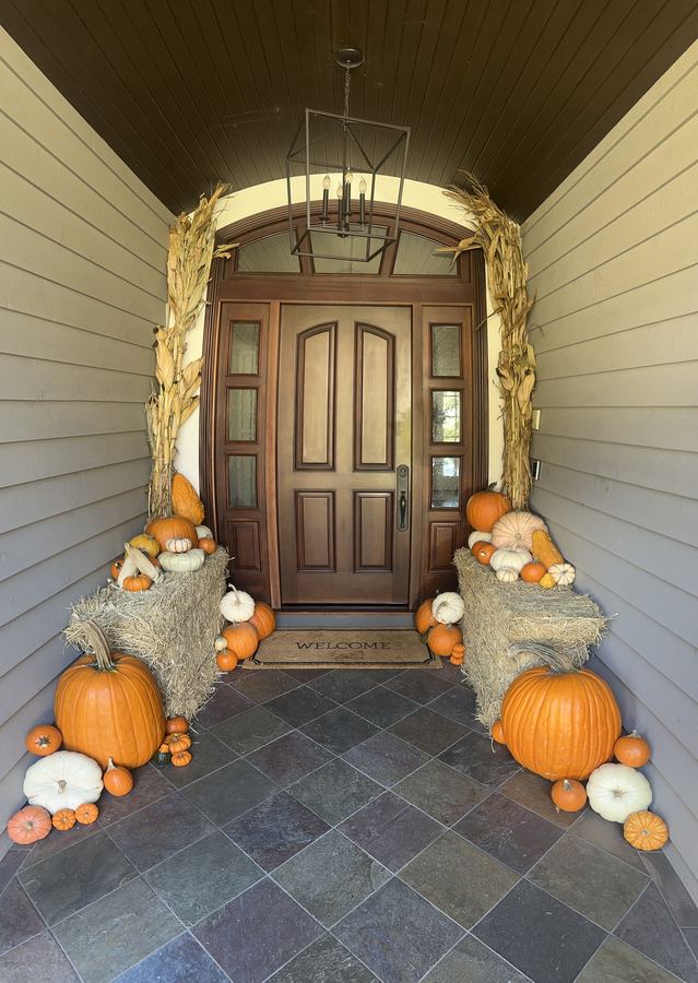 Full porch installation with hay bales, corn stalks and 100+ pumpkins